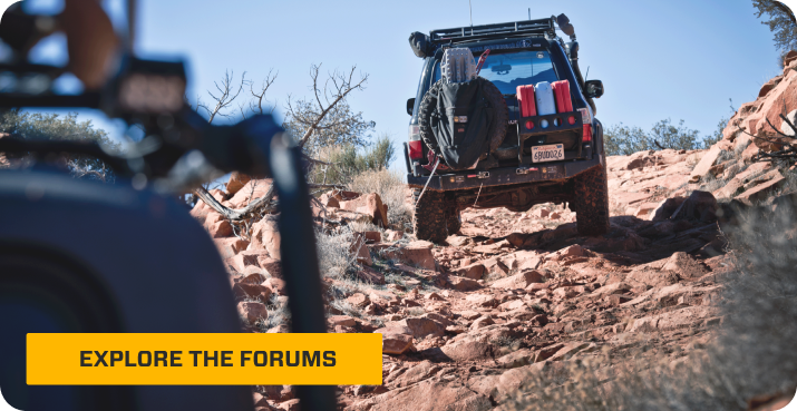 Overland Bound truck driving over rocks in the desert.