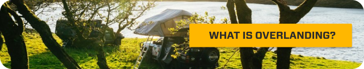 Overland trucks parked next to a lake.